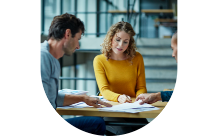 Three persons in an office pointing and reading a paper