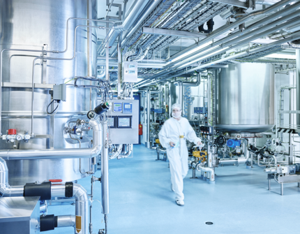 Inside an industrial plant, a laboratory technician is walking
